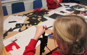 Child cutting out shapes for shadow puppets at after school art club