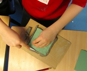 Cutting around templates to create ceramic tiles at the children's art school after school club