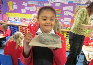 Girl showing her pinch pot bowl in progress at the Children's Art School after school art club