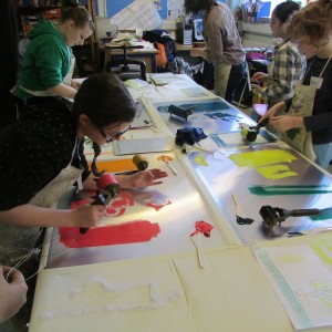 Inking objects at the printing table on the children's art school half term printing course led by artist, Chrys Allan